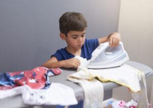 Beispiel von Parentifizierung: Ein zu kleines Kind bügelt Kleidung zu Hause.